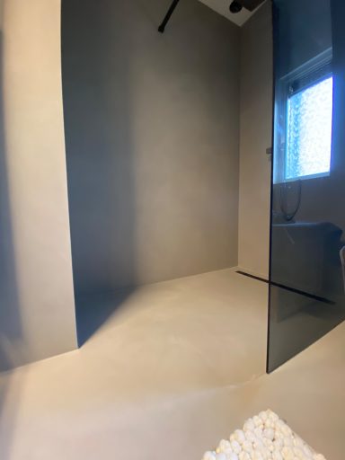 Moderne badkamer met douche, grijze muren en een raam met natuurlijk licht.