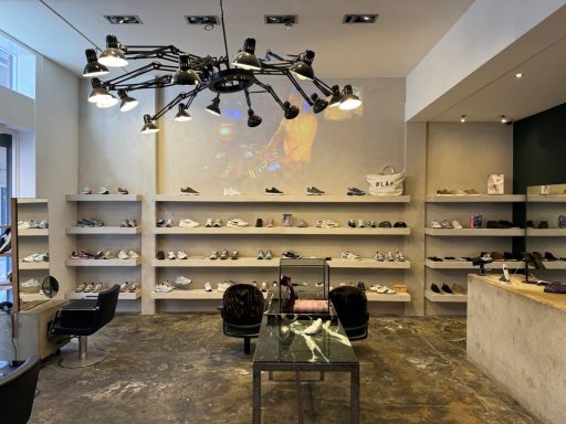 Moderne winkel met schoenen, stijlvolle meubels en een projector aan de muur.