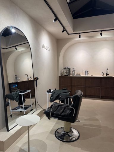 Moderne kappersalon met een grote spiegel, stoel en minimalistische inrichting.